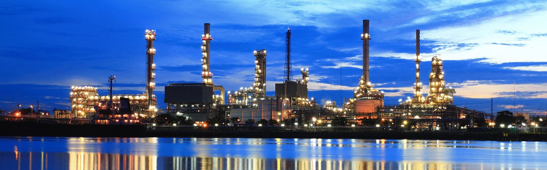 Image of a nuclear site from across the water, dusk. Lots of lights reflecting on the water