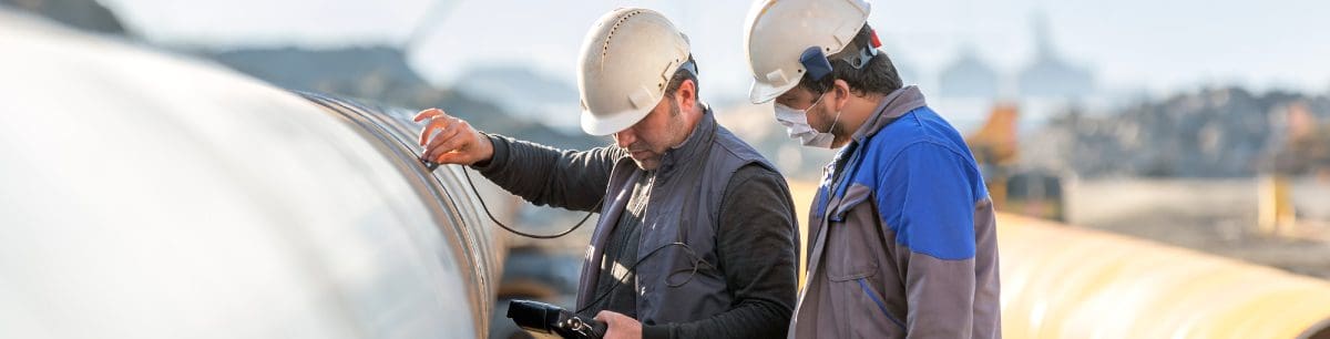 2 technicians using testing equipment on large piping