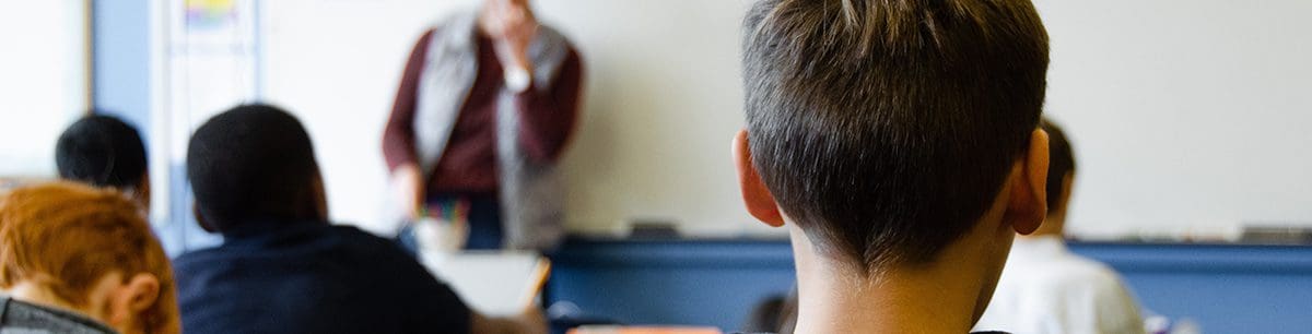 a close up of the back of a boys head in a classroom environment