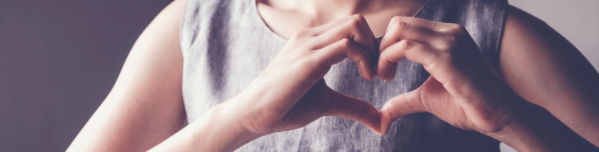 A woman making a heart shape with her hands in from of her chest