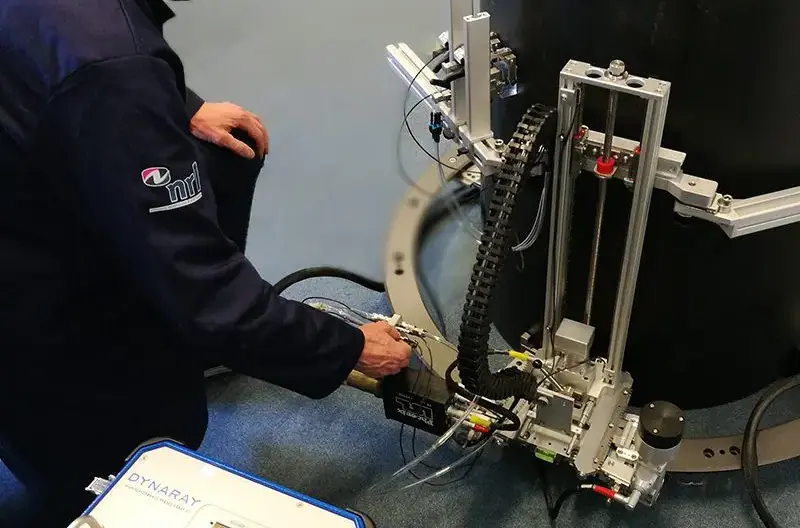 Technician adjusting a mounted inspection device and control unit attached to a large industrial pipe.