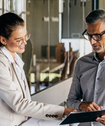 Two colleagues reviewing information together on a tablet in a modern office setting.