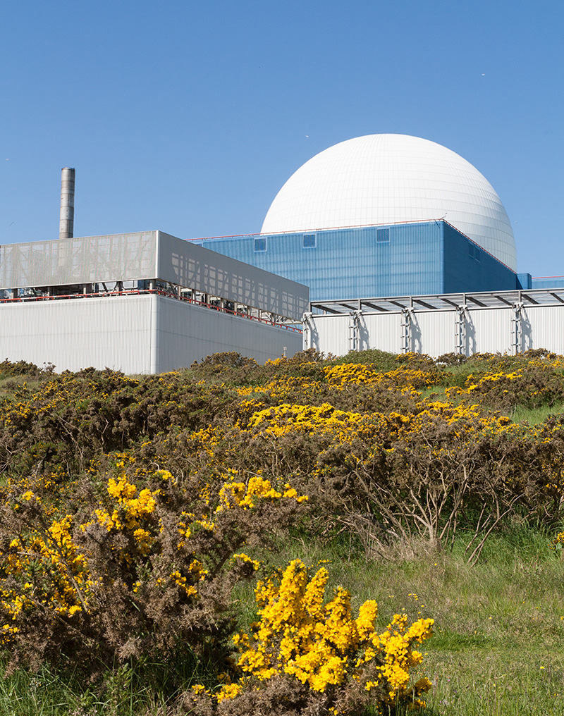 Large industrial building with a white domed structure and surrounding equipment in a field.